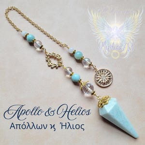 Puede incluir: Un péndulo dorado con una punta de cristal azul claro, adornado con cuentas transparentes y turquesas, y una cadena dorada. Incluye un dije de estrella solar y el texto "Apollo & Helios".