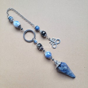 May include: A silver chain with a blue and white stone pendant, a silver ring, and a silver charm with the symbol of the infinity sign. The pendant is a pointed crystal with a silver cap.