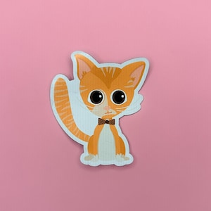 Può includere: Gatto cartone animato arancione e bianco con un papillon marrone. Il gatto guarda a sinistra con occhi grandi.