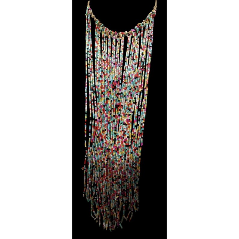 May include: A colorful beaded necklace with a cascade of vertical strands. The beads are a mix of red, blue, yellow, and black. The necklace is suspended from a natural-colored cord, creating a striking, bohemian-inspired accessory.
