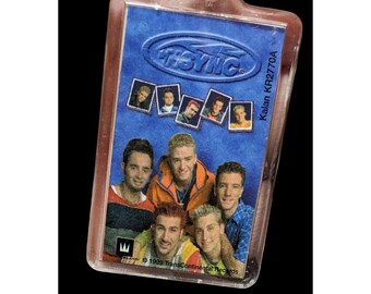 May include: A clear plastic keychain with a blue background featuring a group photo of the boy band *NSYNC. The keychain has the band's logo and the text "Kalan KR2770A" printed on it. The text "© 1999 TransContinental Records" is also printed on the keychain.