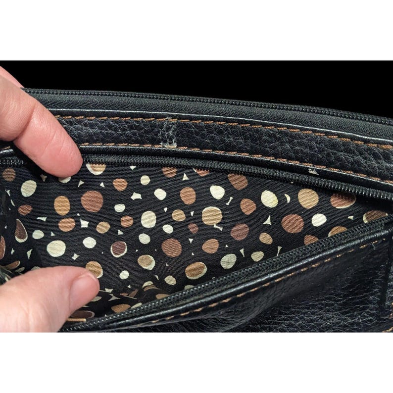 May include: Black leather wallet with a zipper closure and a brown and white polka dot lining.
