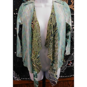 May include: A light blue and green open front jacket with a waterfall design. The jacket has a textured pattern and features two zippered pockets. The draped front panels are patterned with shades of green, brown, and black.