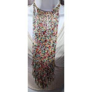 May include: A colorful beaded necklace with a cascade of small, rectangular beads in various colors, including red, yellow, green, and black. The necklace is displayed on a mannequin and has a neutral-colored cord.