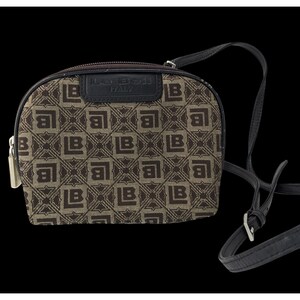 May include: A small, brown and tan crossbody bag with a repeating geometric pattern. The bag has a black strap and a zip closure. The brand name "La Bell" is visible on the top of the bag.