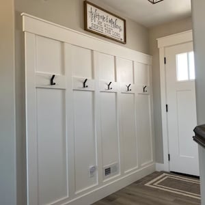 May include: White wainscoting with black hooks on a wall in a hallway. A wooden sign above the wainscoting reads "As for me and my house, we will serve the Lord."
