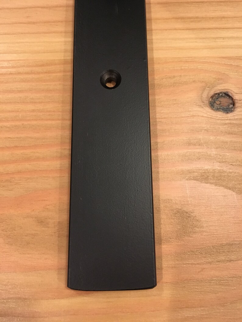 May include: A black metal bar with a rounded edge and a single hole in the center.
