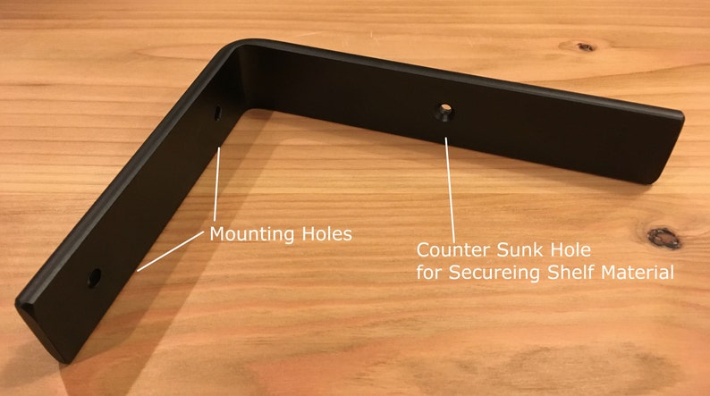 May include: Black metal shelf bracket with two mounting holes and a countersunk hole for securing shelf material.