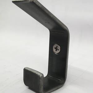 May include: A metal hook with a single screw for mounting. The hook is made of a dark gray metal and has a simple, industrial design.