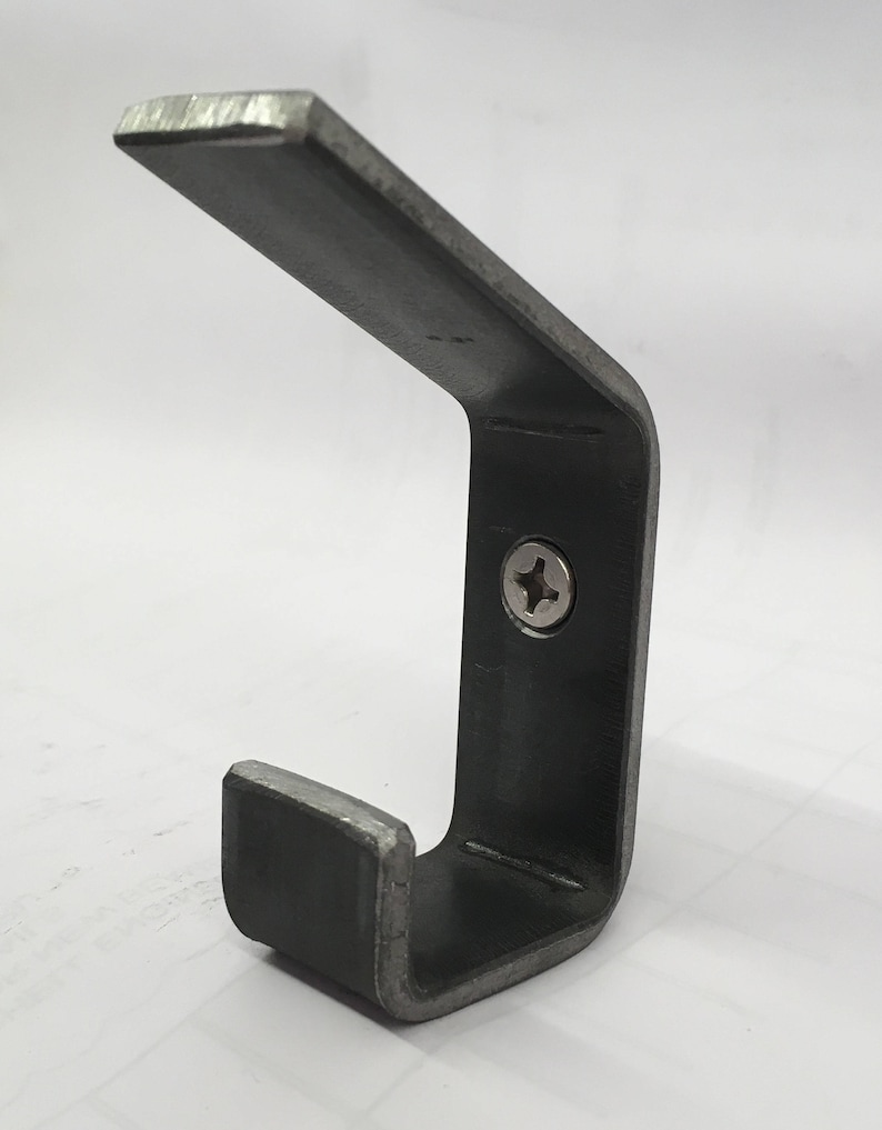 May include: A metal hook with a single screw for mounting. The hook is made of a dark gray metal and has a simple, industrial design.