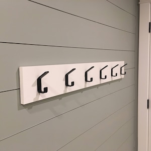 metal double coat hooks mounted on to board.