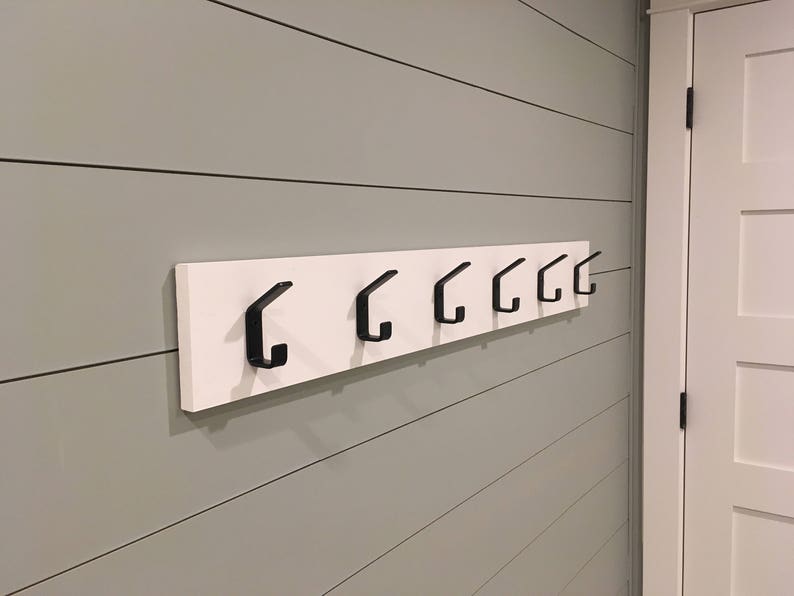 metal double coat hooks mounted on to board.