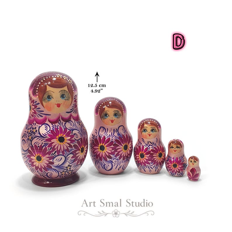 Variante D : poupées gigognes russes en bois avec finition nacrée violet framboise, décorées de grandes fleurs peintes à la main. Collection artisanale de 5 matriochkas à emboîter, inspirée du folklore russe.
