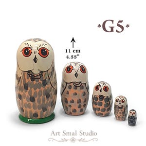 May include: A set of five nesting dolls shaped like owls, featuring orange eyes and brown and gray speckled plumage. The largest doll is 11 cm tall. The text *G5* appears in the upper right corner, and Art Smal Studio is printed at the bottom.