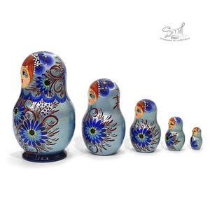 Vue de profil de la matriochka russe bleue révélant les détails de la peinture florale réalisée à la main. Les cinq poupées gigognes en bois mettent en valeur le décor sur les côtés et la finition nacrée brillante de cette collection exclusive.