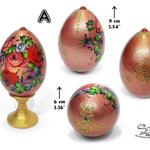 Œuf de Pâques peint à la main en style russe, finition rose nacrée, décor floral avec ornements dorés et détail bijou, présenté sous différents angles avec socle décoratif et mesure 12,5 cm de haut