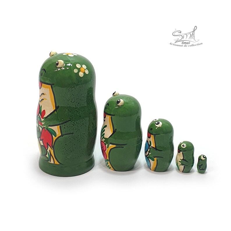 Viewed from the back, the five green frog nesting dolls reveal their hand-painted floral details, rounded wooden forms, glossy finish, and traditional nesting construction