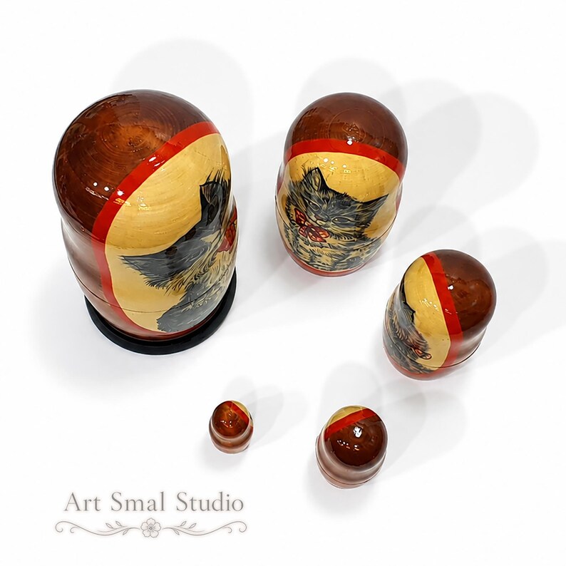 Overhead view of hand painted Russian nesting dolls featuring cat portraits, showing the glossy wooden tops and traditional Matryoshka craftsmanship with soft natural shadows.