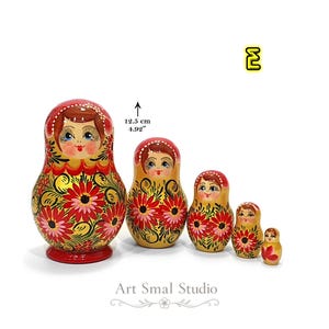 Variante E : matriochka russe aux tons jaune doré nacré, ornée de fleurs rouges et roses peintes à la main. Ensemble de cinq poupées en bois inspiré de l'art traditionnel russe, création artisanale de la collection Zoia.