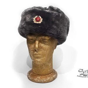 Op de afbeelding: Een grijze imitatiebont ushanka-muts met een rode ster en een hamer-en-sikkel-embleem.
