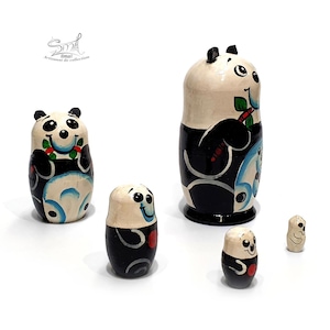 Side view of a five-piece panda matryoshka nesting doll set, showing the hand-painted Russian wooden dolls from different angles with their black, white, blue, green and red decorative details.