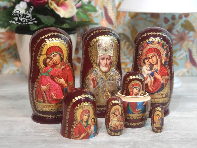 Matriochka Russe Religieuse – Une œuvre d’art spirituelle en bois peint, représentant des icônes orthodoxes telles que la Vierge Marie, l’Enfant Jésus, Saint Nicolas, et les icônes Vladimirskaya et Kazanskaya. Une poupée traditionnelle pleine de foi et de symbolisme.