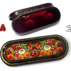Puede incluir: Dos estuches para gafas de forma ovalada. El estuche superior es negro con un interior rojo. El estuche inferior es negro con un borde dorado y un dise&ntilde;o floral pintado en la tapa. El dise&ntilde;o presenta flores rojas, naranjas, amarillas y blancas sobre un fondo marr&oacute;n.