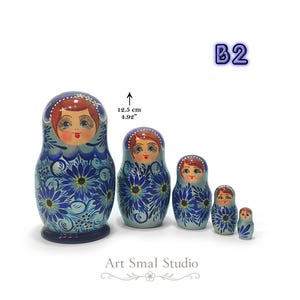 Variante B2 de la matriochka russe : ensemble de 5 poupées gigognes en bois peintes à la main, décor floral bleu nacré et finition brillante. Présentation des cinq poupées emboîtables avec dimensions de la plus grande (12,5 cm).