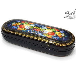 Puede incluir: Caja de madera lacada en negro con un dise&ntilde;o floral pintado en colores vivos. La caja tiene un borde dorado y est&aacute; decorada con un patr&oacute;n floral. La caja est&aacute; cerrada y se encuentra sobre una superficie blanca.