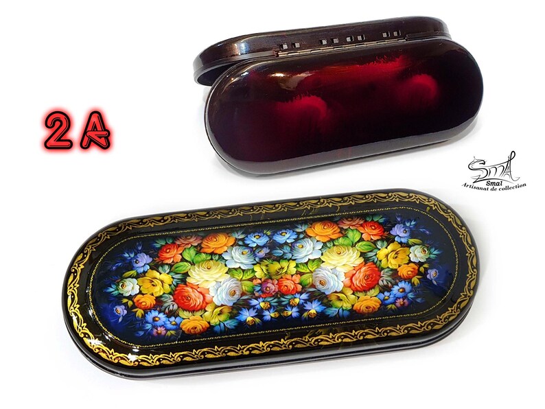 Puede incluir: Una caja lacada en negro con un dise&ntilde;o floral y una tapa a juego. La caja est&aacute; decorada con un patr&oacute;n floral colorido y tiene un borde dorado. La tapa est&aacute; cerrada y tiene un peque&ntilde;o pestillo.