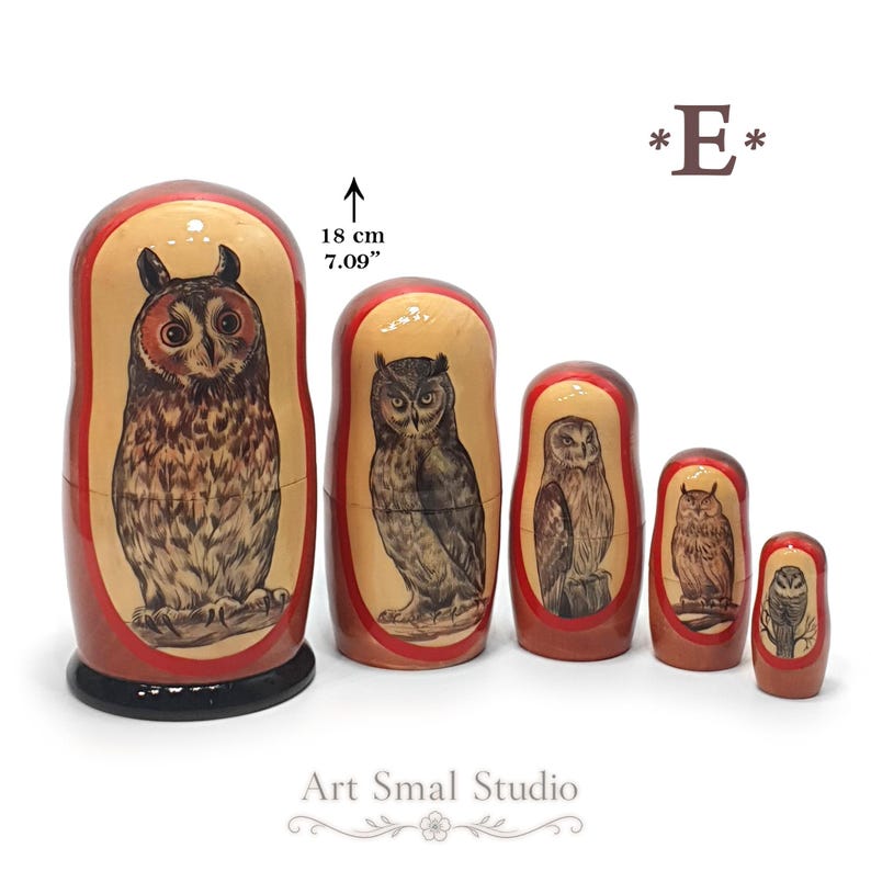 Five Russian nesting dolls featuring hand-painted owls. The largest doll depicts a long-eared owl with prominent ear tufts, a warm reddish-brown facial disk, and richly detailed brown and cream plumage, followed by four smaller owls in different poses and markings. The 18 cm set is arranged from largest to smallest on a white background. Model E