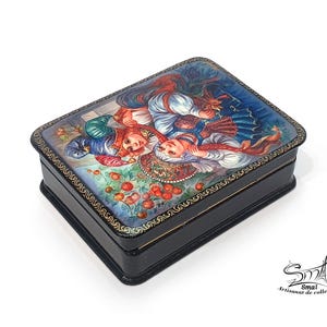 Boîte russe laquée en papier mâché vue en angle, décor Ivan Tsarévitch et Vassilissa la Belle avec l’Oiseau de Feu, coffret folklorique vernis brillant avec motif doré peint à la main