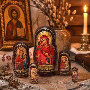 May include: A set of five dark brown nesting dolls featuring hand-painted icons of the Virgin Mary and Child in vibrant red and blue robes. Each doll is decorated with intricate gold leaf detailing along the edges and base, showcasing traditional religious artistry with a glossy finish.
