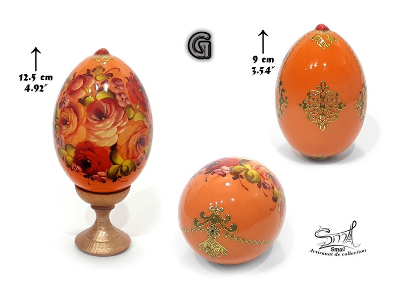 Œuf de Pâques en teinte orange clair nacré, orné d’un décor floral peint à la main inspiré de l’art russe, sublimé par des motifs dorés délicats, avec socle inclus, hauteur totale 12,5 cm, hauteur de l’œuf 9 cm
