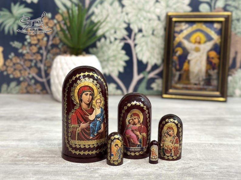 May include: A set of six Russian nesting dolls, each featuring religious iconography. The dolls are painted in deep red with gold accents and depict figures with halos. The largest doll is approximately 6 inches tall.