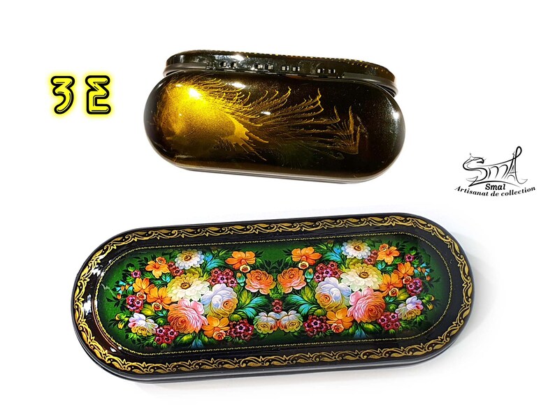 Puede incluir: Dos cajas ovaladas de laca negra con detalles dorados. La caja m&aacute;s peque&ntilde;a tiene un fondo dorado con un dise&ntilde;o de pluma de pavo real. La caja m&aacute;s grande tiene un fondo verde con un dise&ntilde;o floral. Ambas cajas est&aacute;n decoradas con bordes dorados.
