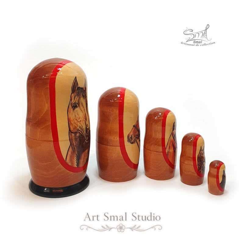 Side view of five wooden horse nesting dolls, revealing the hand painted equestrian designs, natural wood grain, red detailing, and graduated sizes of the Russian doll set