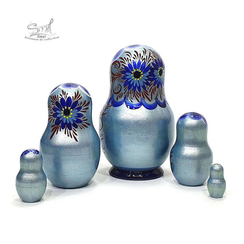 Vue arrière des poupées gigognes russes bleu nacré de la collection Zoia. Les cinq matriochkas en bois dévoilent une peinture artisanale réalisée sur toute la surface, avec de délicats motifs floraux et une finition brillante.