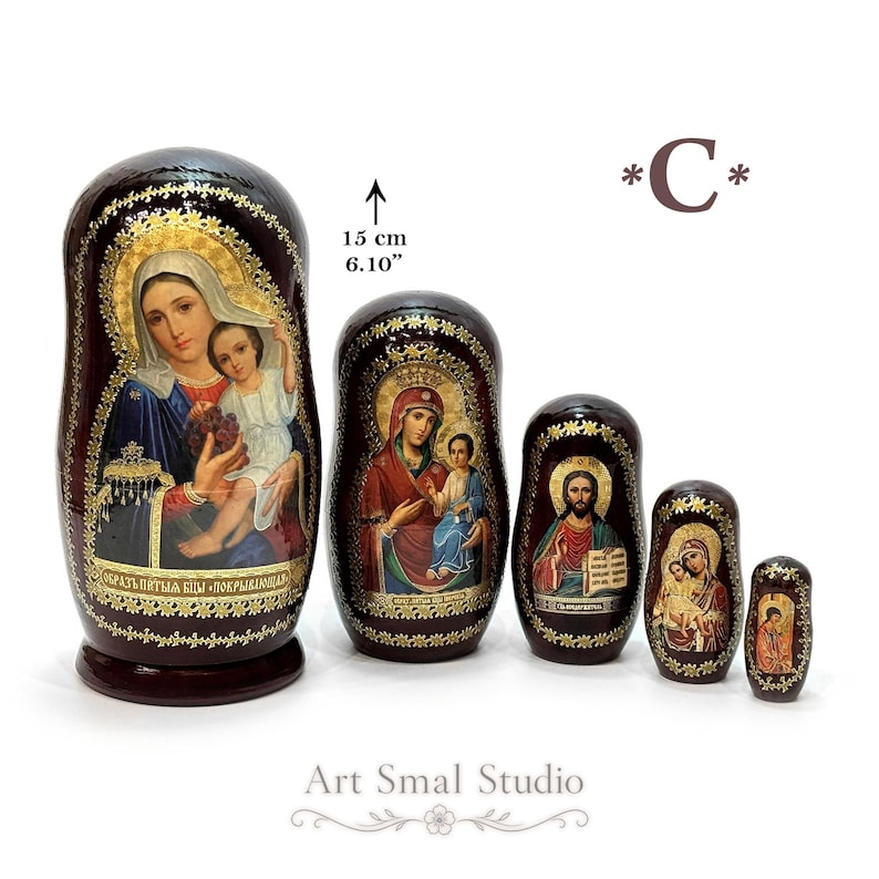 A set of five nested religious matryoshka dolls, each hand-painted with Orthodox icons on a dark background with gold patterns. The largest doll, measuring 15 cm (5.91 inches), features the "Umilenie" icon of the Virgin Mary and Child Jesus. The smaller dolls depict other Orthodox icons, including the "Joy of All Who Sorrow" Mother of God, Christ Pantocrator, another Virgin Mary with Child, and an Orthodox male saint.