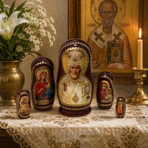 Russian Orthodox Matryoshka set of 5 with Saint Nicholas and sacred icons, hand-painted wooden nesting dolls displayed on an embroidered tablecloth