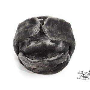 Op de afbeelding: Een grijze imitatiebont ushanka-muts met een omklapbare oorflap. De muts is gemaakt van zacht, pluche materiaal en heeft een klassiek ontwerp.