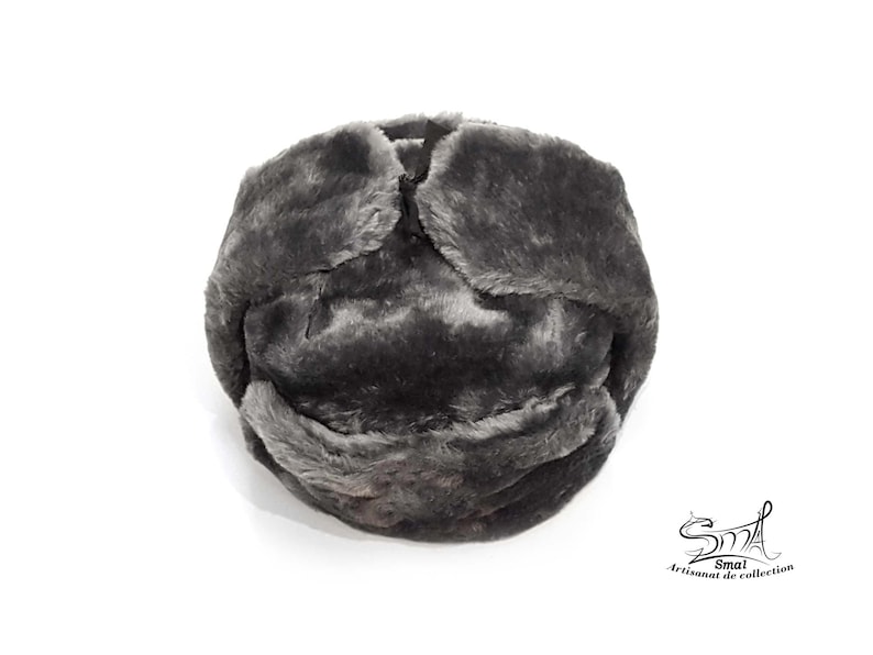Op de afbeelding: Een grijze imitatiebont ushanka-muts met een omklapbare oorflap. De muts is gemaakt van zacht, pluche materiaal en heeft een klassiek ontwerp.