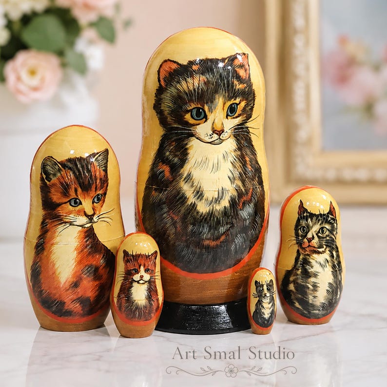Close-up of a hand painted wooden Matryoshka doll set with adorable cat illustrations arranged on a light marble surface in a cozy pastel room.
