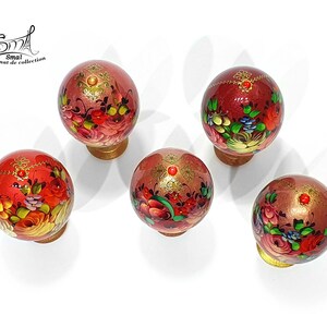 Vue de dessus d’un ensemble d’œufs de Pâques style russe, décor floral peint à la main, finition nacrée avec ornements dorés et cabochons rouges, présentés avec leurs socles décoratifs