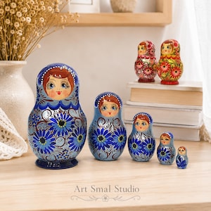 Ensemble de 5 poupées russes Matriochka en bois, peintes à la main avec une finition nacrée bleue, présenté dans un intérieur chaleureux. Décoration artisanale russe avec motifs floraux traditionnels et édition limitée Zoia.