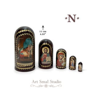May include: A set of five dark brown nesting dolls featuring religious iconography. The largest doll measures 11 cm or 4.33 inches in height. Each piece is decorated with gold-toned floral borders and detailed paintings of biblical scenes.