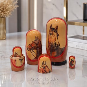 Horse nesting doll set with five hand painted wooden figures arranged on a modern marble surface, showing detailed equestrian artwork and elegant reflections