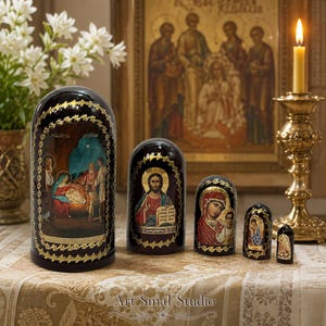 Hand-painted Russian Orthodox Nativity nesting doll set of 5 featuring the Birth of Christ icon, glossy wooden Matryoshka dolls displayed on a decorative table with candles and religious icons.