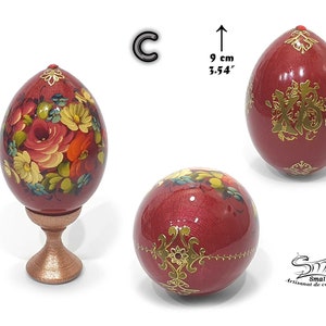 Œuf décoratif de Pâques en style russe, surface violette irisée, composition florale peinte à la main, rehaussée d’ornements dorés et d’un détail bijou, présenté sur socle, hauteur totale 12,5 cm, œuf seul 9 cm