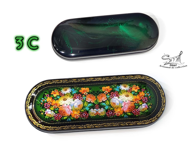 Puede incluir: Un estuche para gafas rectangular negro y verde con un dise&ntilde;o floral. El estuche est&aacute; decorado con detalles dorados y tiene un fondo negro con flores verdes y blancas.